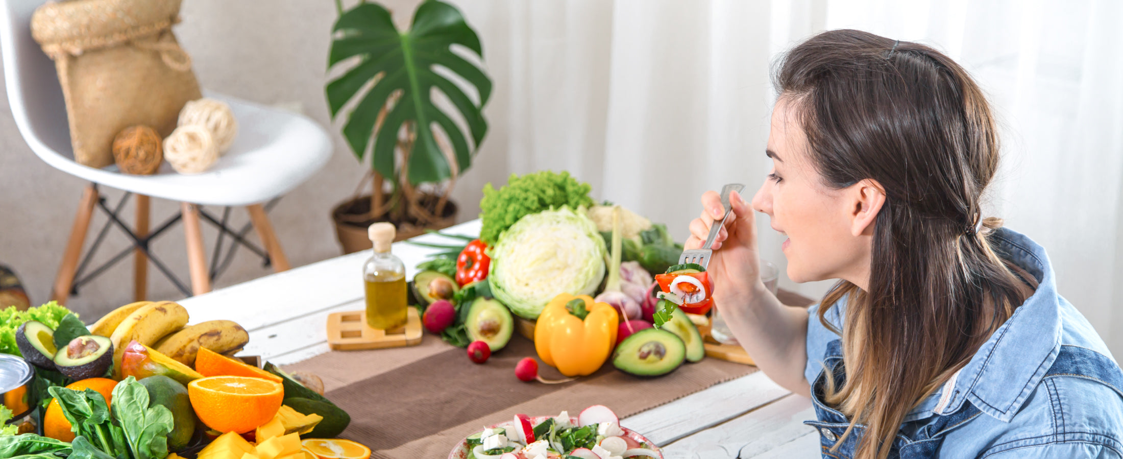 image of a woman eating salad next to a table full of fruits and veggies